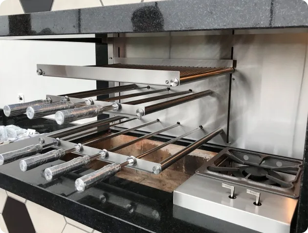 Cooktop embutido na bancada, ao lado de uma churrasqueira rotativa